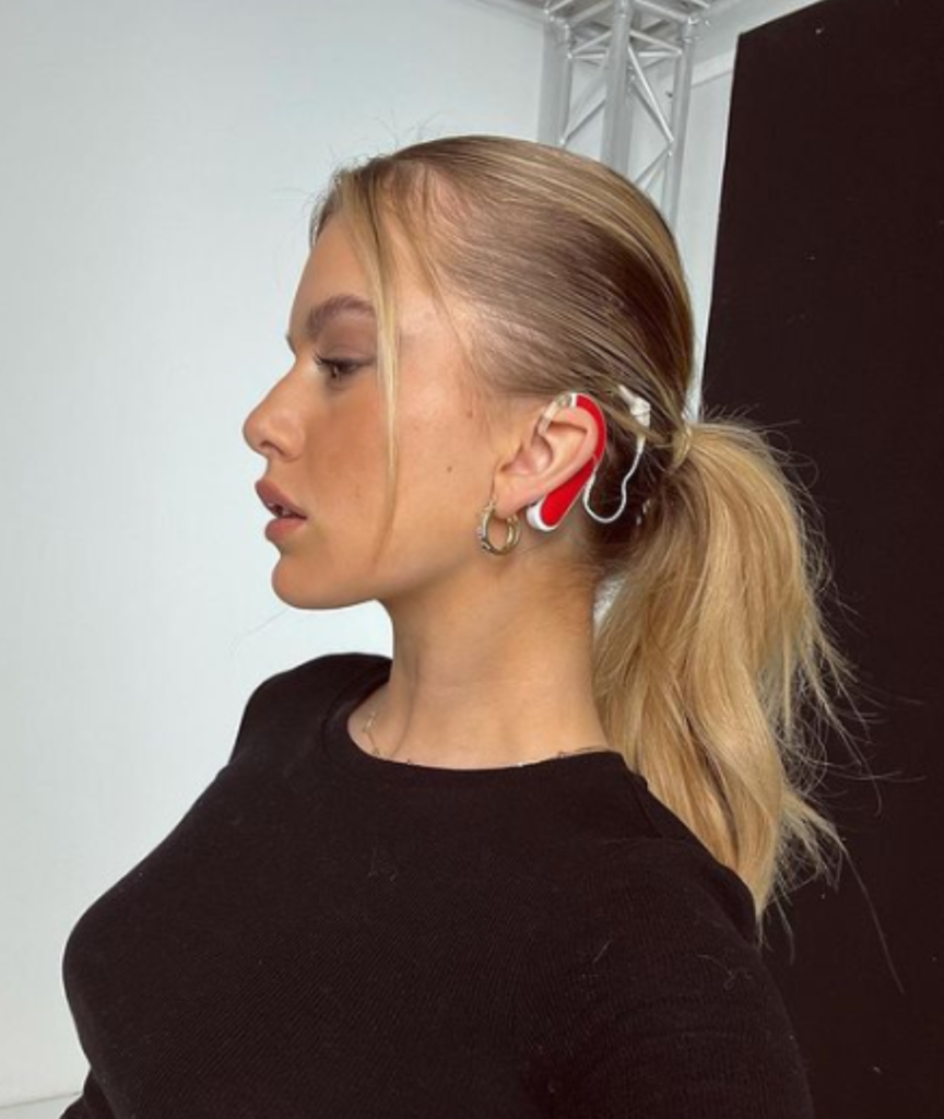 Lady with blonde hair and red coloured cochlear implant